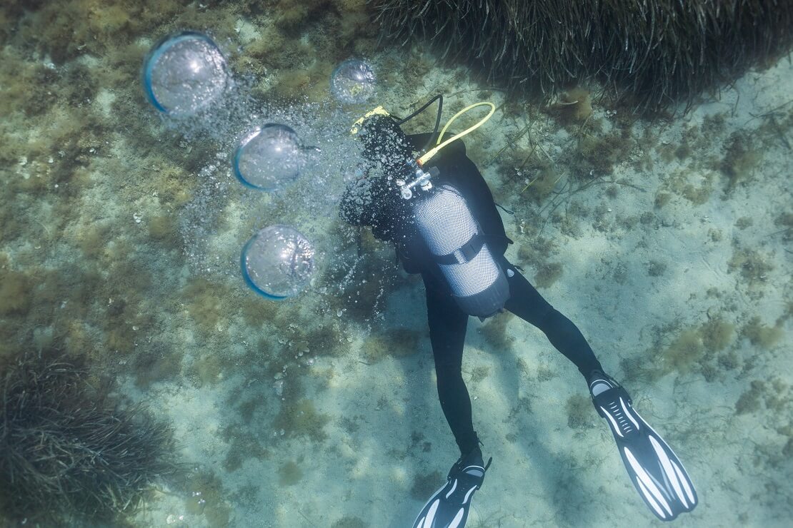 Taucher am Grund unter Wasser wirft Blasen
