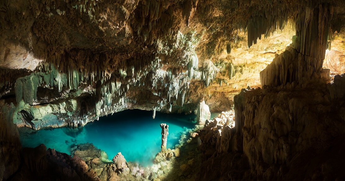 Eine Höhle mit türkis blauem Wasser von der Decke hängen Stagnierten