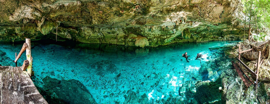Taucher sind in einer Höhle in türkisblauem Wasser