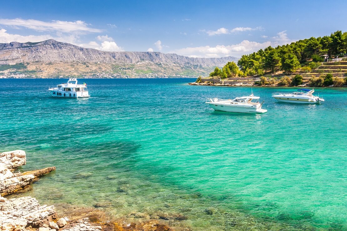 Küste der Kroatischen Adria mit türkisem Meer und Booten auf dem Wasser