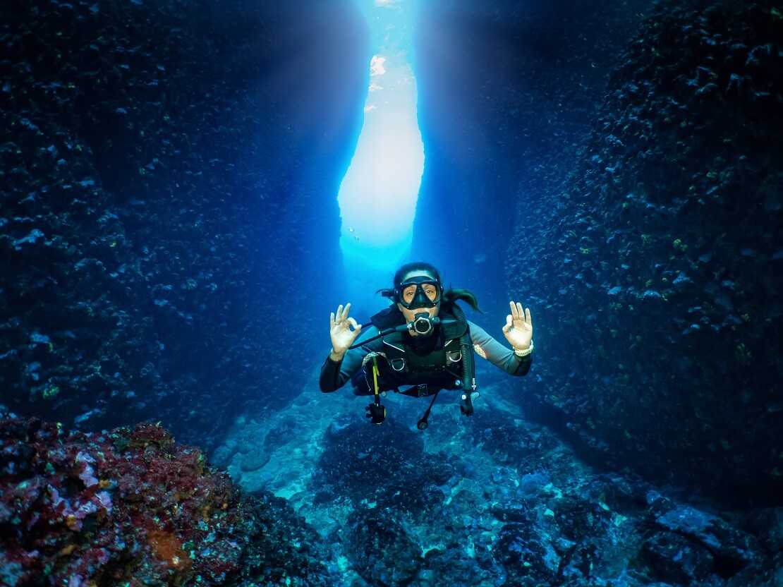 Taucherin vor einer Höhle unter Wasser zeigt das alles OK ist