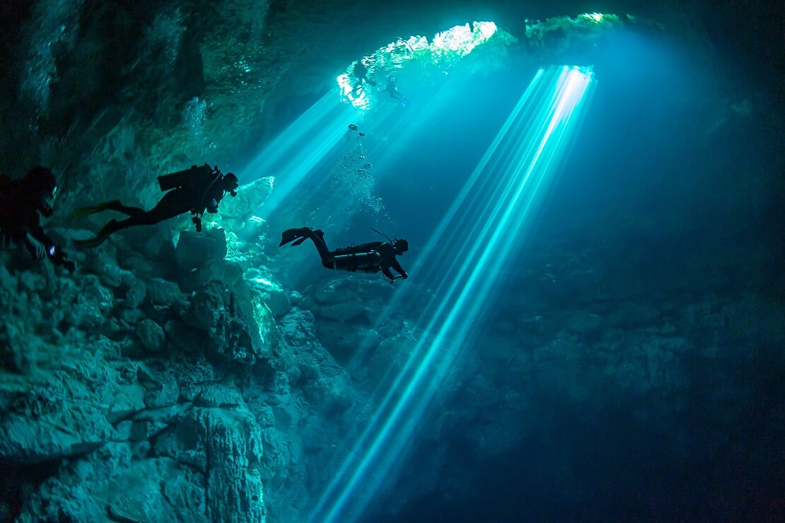 Taucher in einer Höhle unter Wasser im türkis blauen Meer