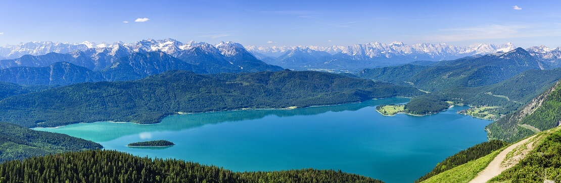 Ansicht des Walchensees türkis blauer See umgeben von den Alpen und einem Wald