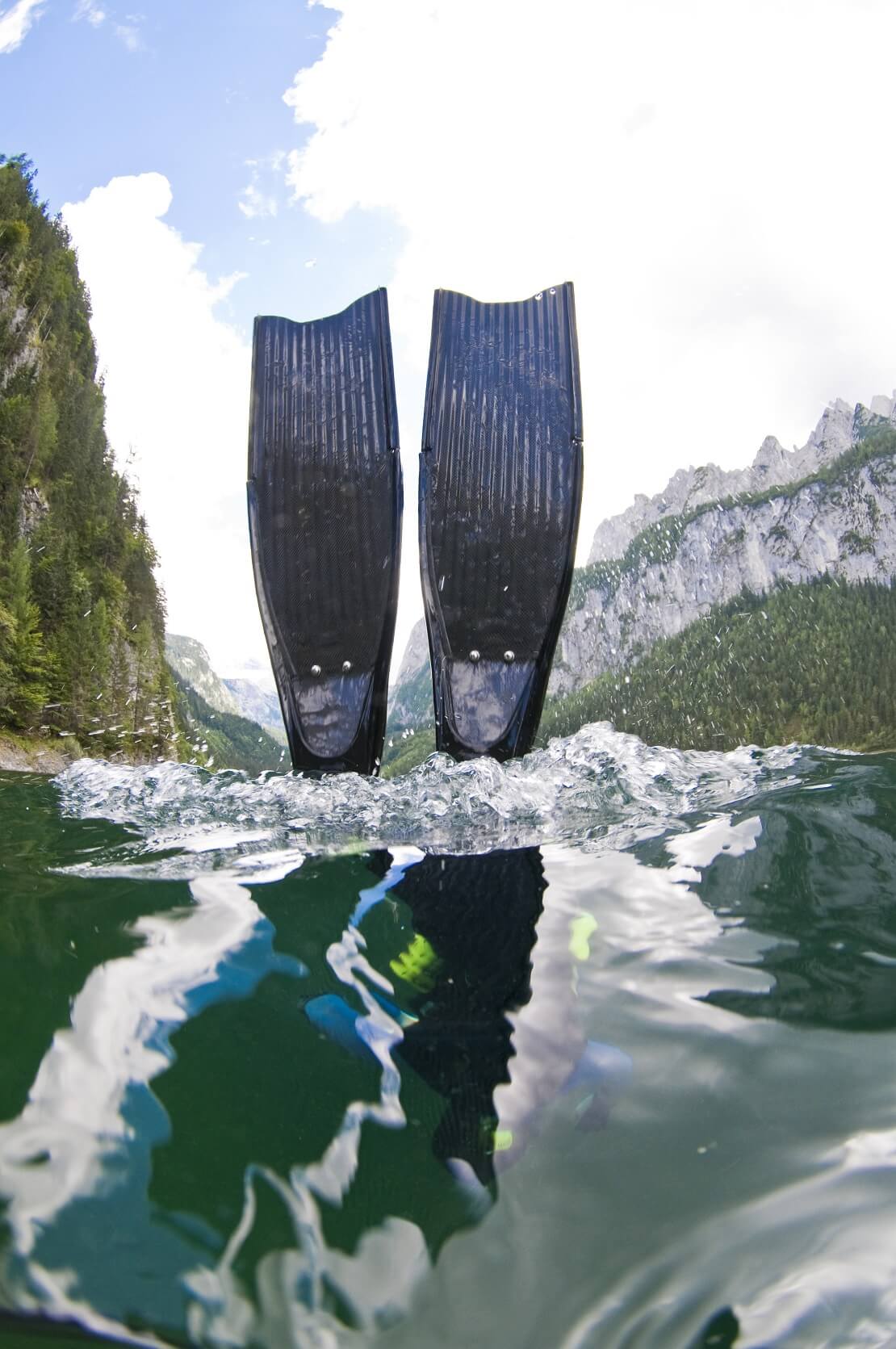 Apnoeflossen im Wasser im Hintergrund sind Berge zu sehen