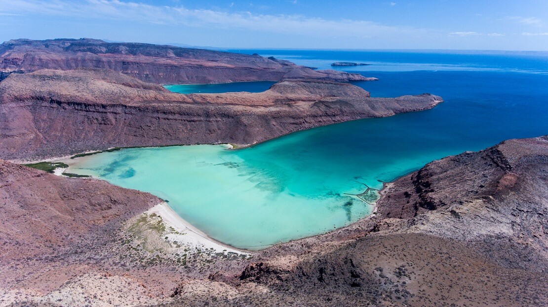 türkisblaues Meer umgeben von einer Steinigen Küste und felsigen Bergen