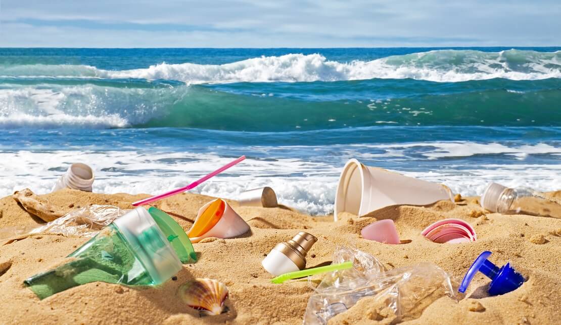 Müll liegt auf einem Sandstrand im Hintergrund ist das Meer