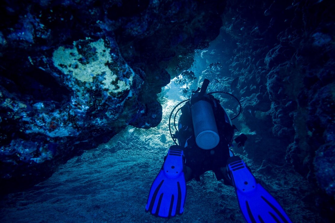 Taucher taucht durch eine schmale Höhle