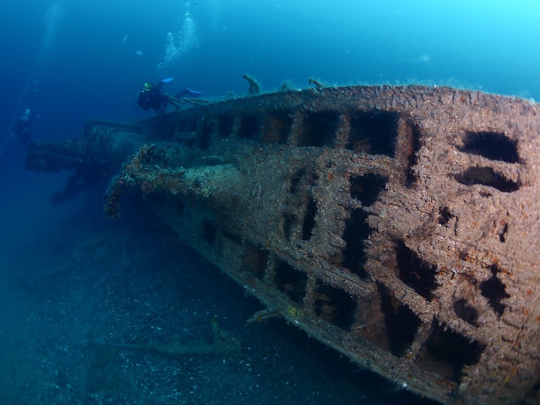 Taucher schwimmen um ein versunkenes U-Boot herum