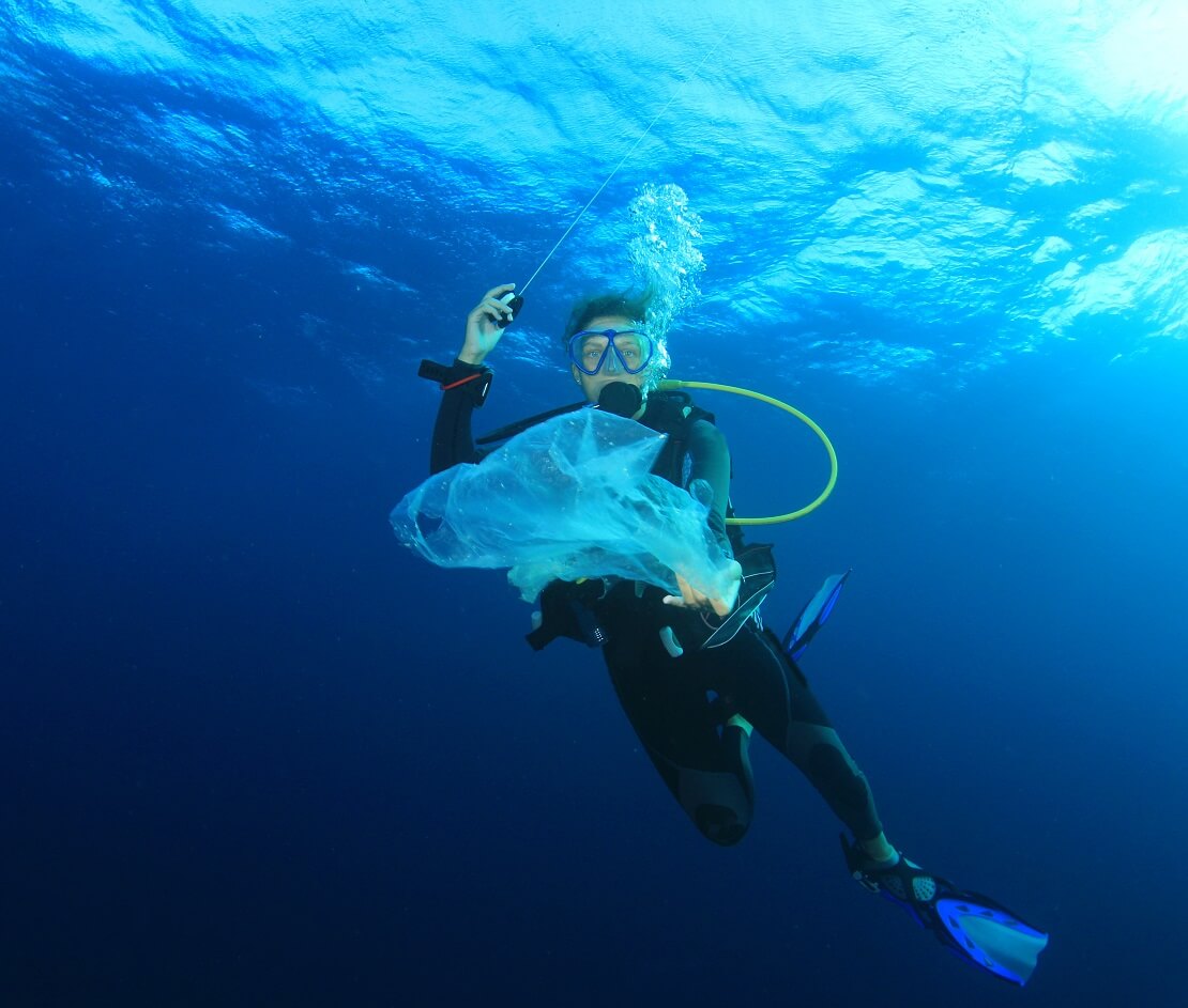 Taucher unter Wasser mit einer Plastiktüte in der Hand