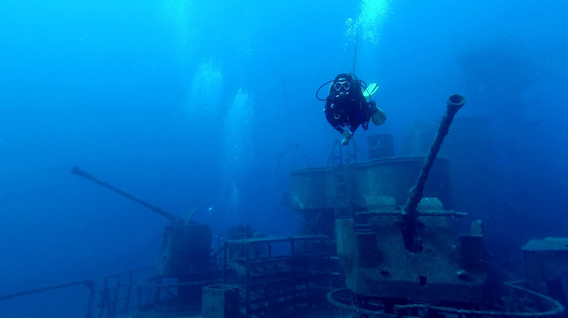 Taucher schwimmt über einem Schiffswrack