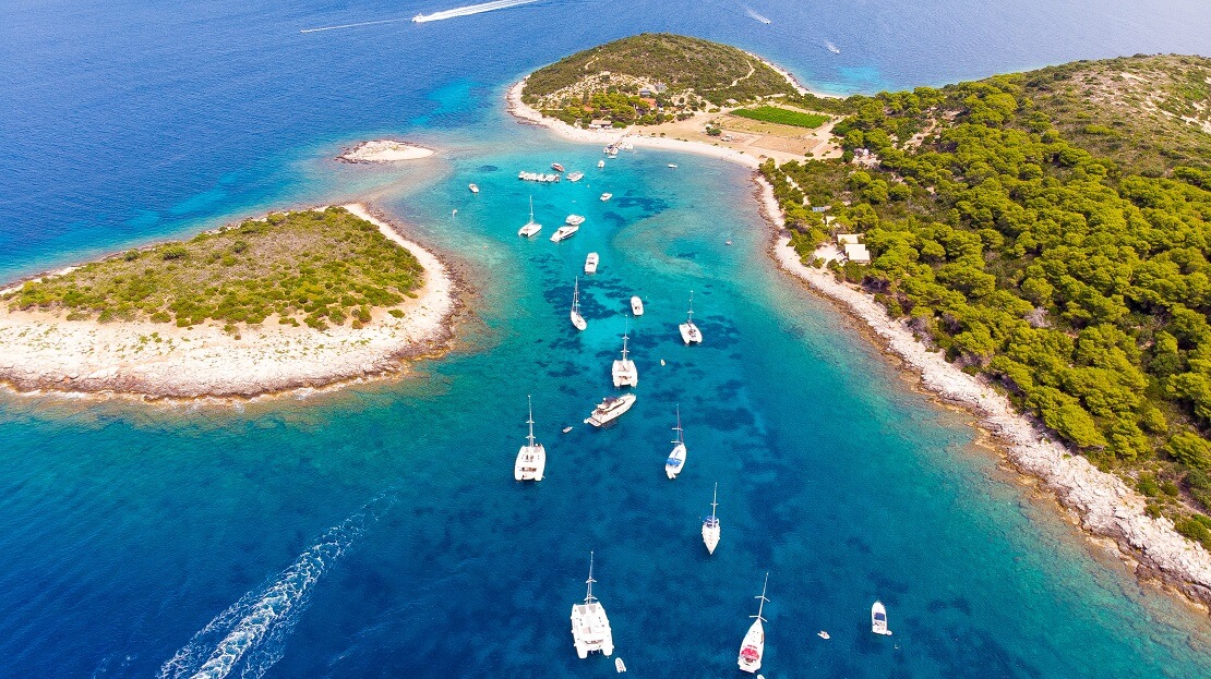 Boote schwimmen vor einer Küste im türkisblauen Meer