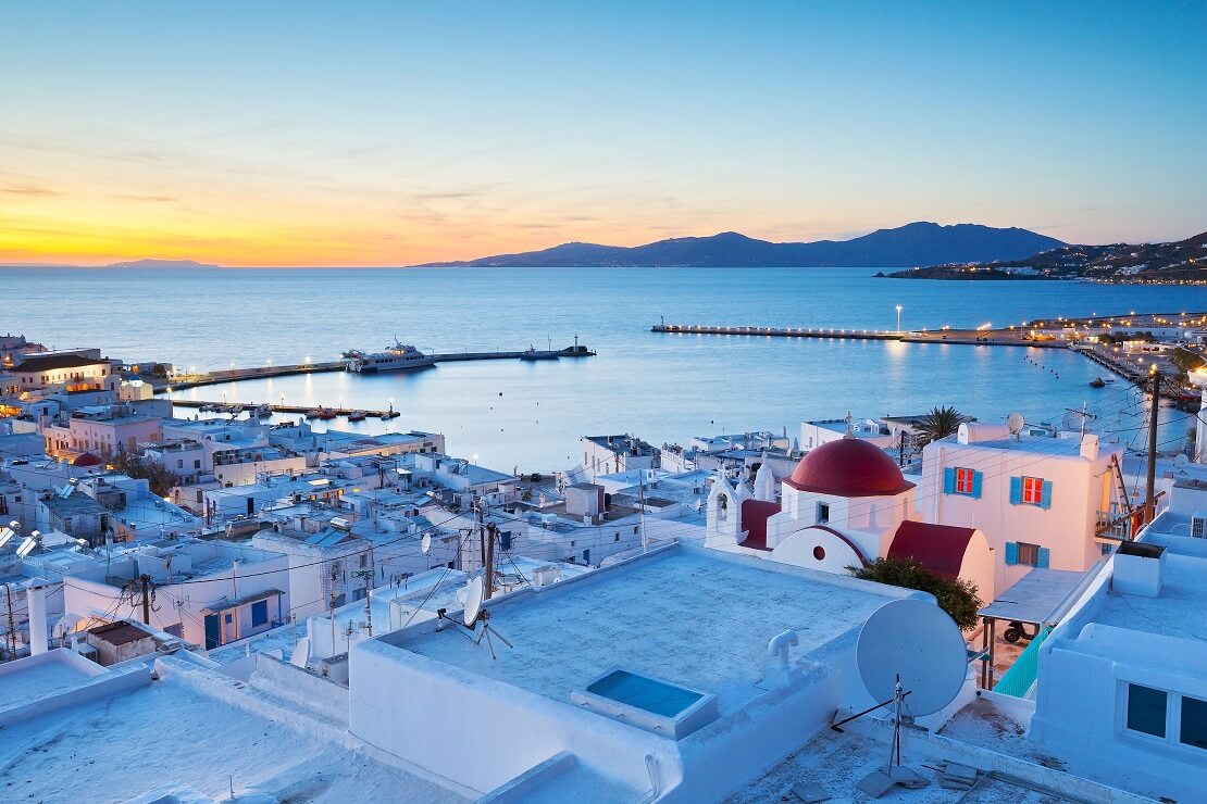 Blick auf Mykonos am Abend im Vordergrund die Häuser im Hintergrund das Meer