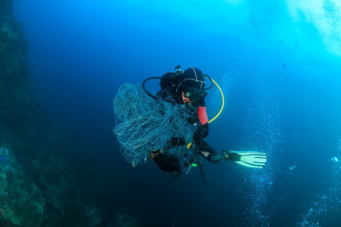 Taucher schwimmt mit einem Fischernetz in der Hand