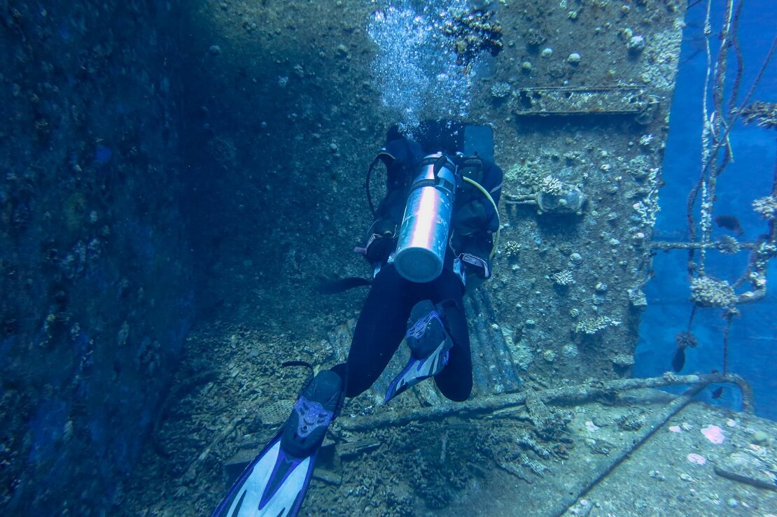 Taucher mit Ausrüstung an einem Schiffswrack