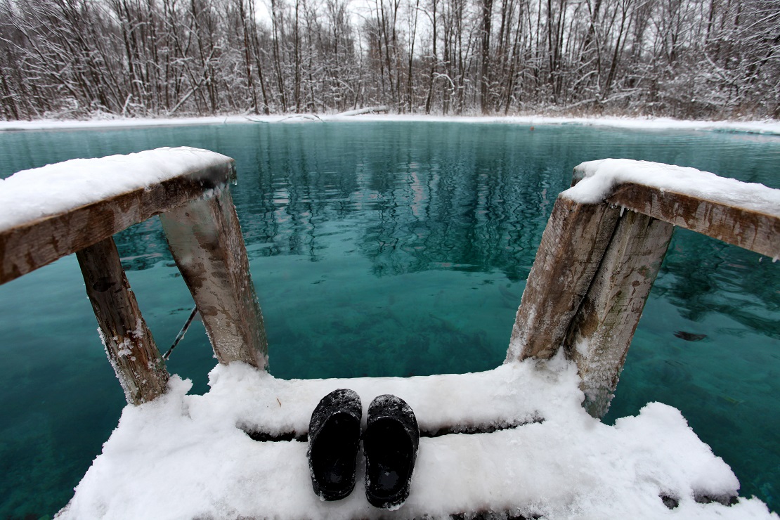 Holzbrücke mit Schnee an einem türkisblauen See