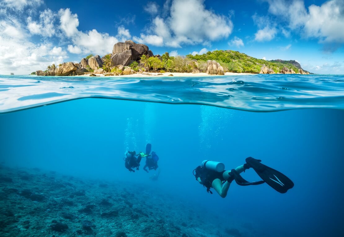 Taucher schwimmen unter Wasser im Hintergrund eine Insel