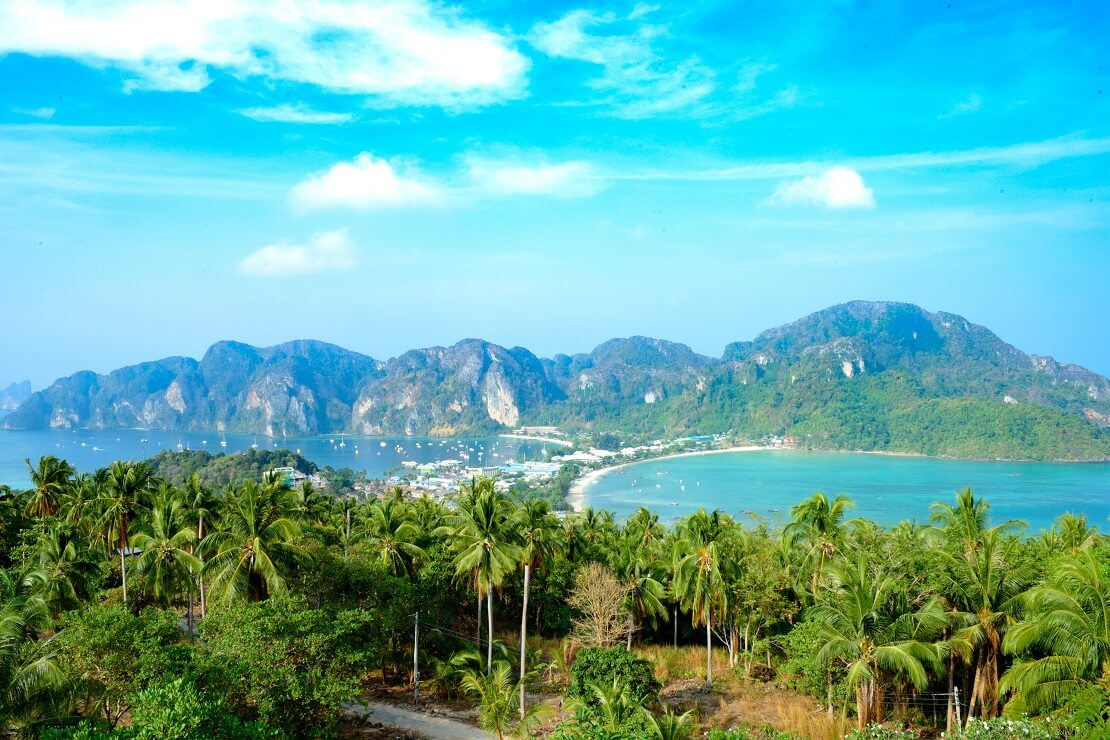 Anblick auf eine Insel mit Palmen und dem Meer im Hintergrund sind hohe Berge