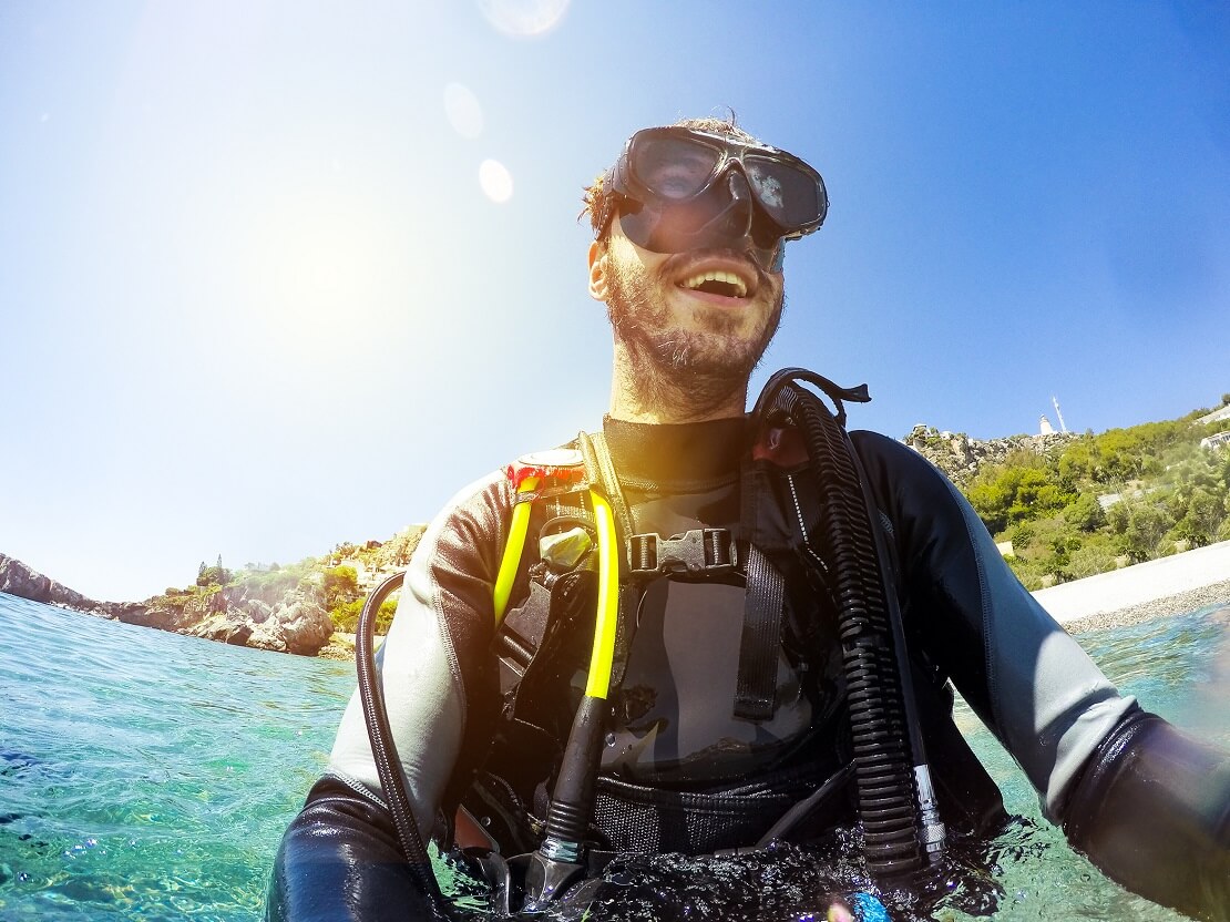 Taucher lacht bei seinem Einstieg in das Wasser