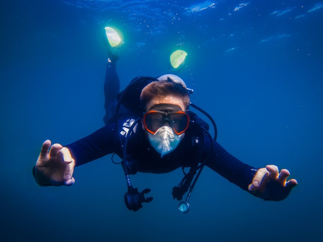 Taucher mit einer Mund-Nasen-Maske im Wasser