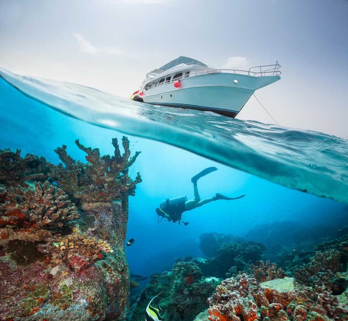 Taucher unter Wasser schwimmt unter einem Boot