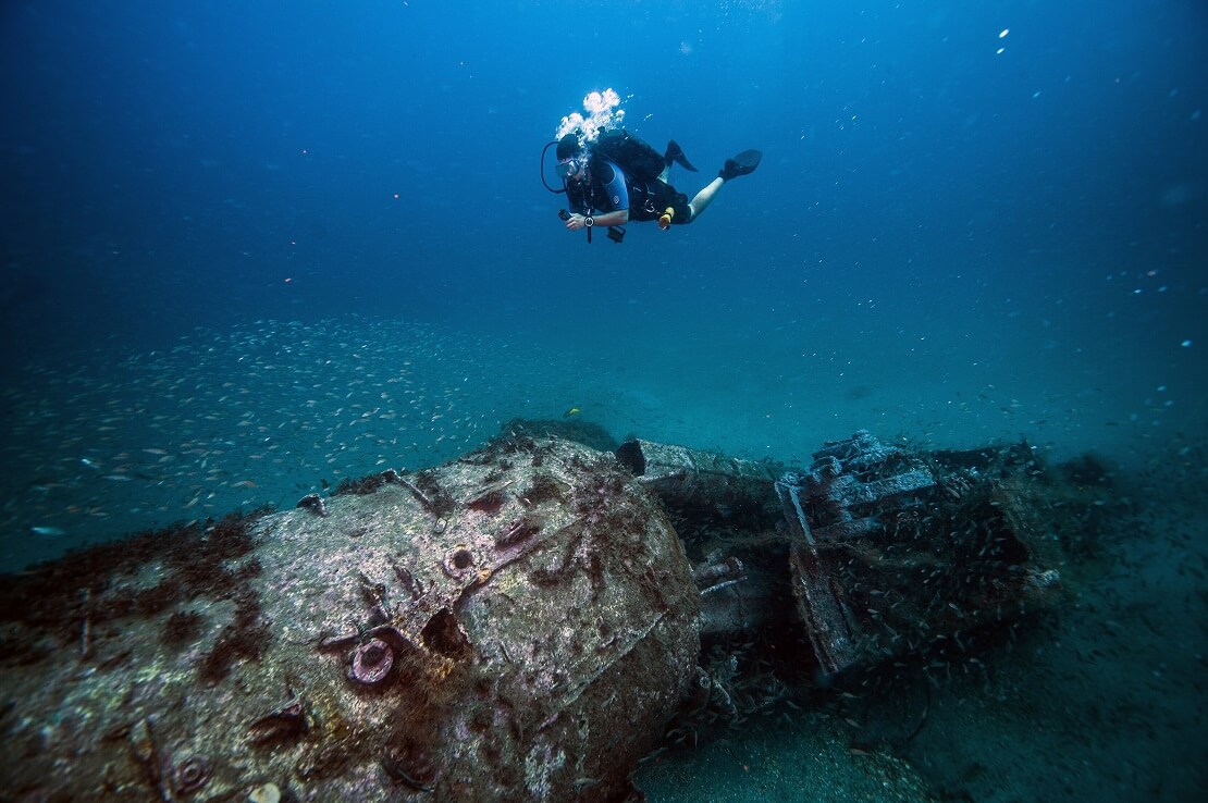 Ein Taucher schwimmt über das Wrack der U-352