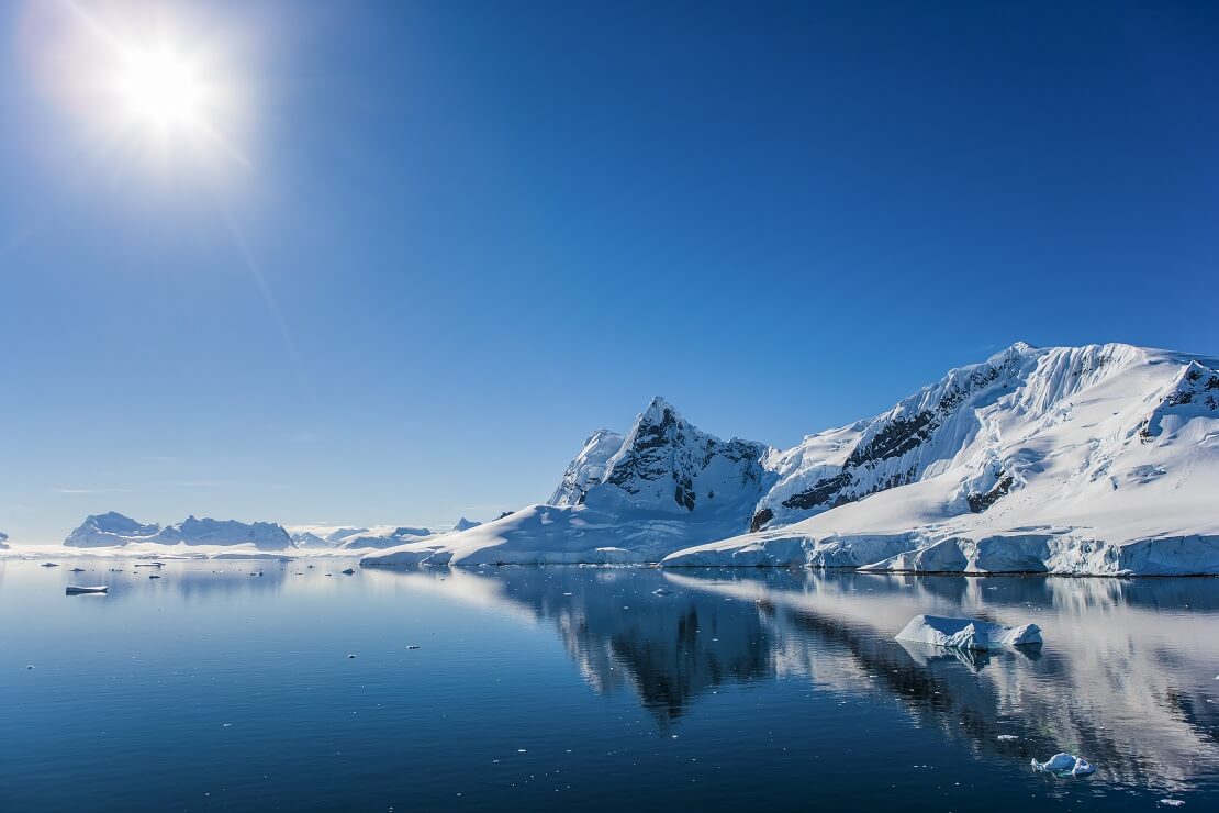 Die Antarktis mit tiefblauem Wasser und weißen Bergen