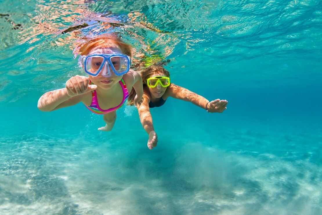 Zwei Kinder mit Tauchmasken unter Wasser