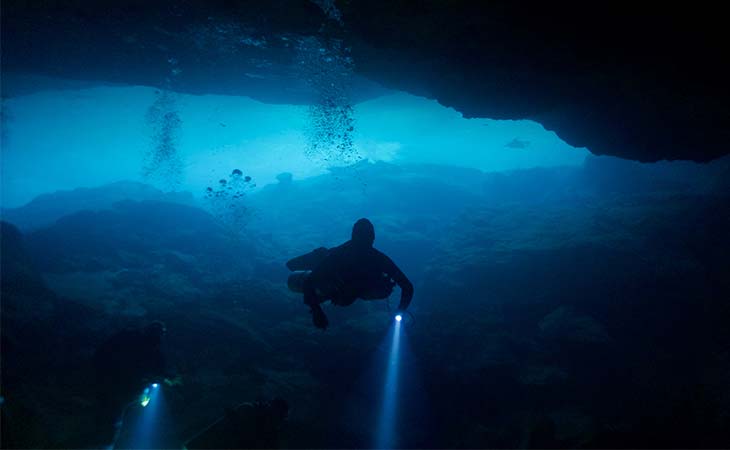Zwei Taucher erforschen mithilfe einer technischen Tauchausrüstung eine Unterwasserhöhle.