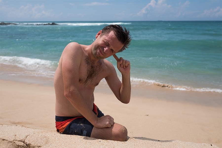 Mann am Strand mit Ohrenschmerzen